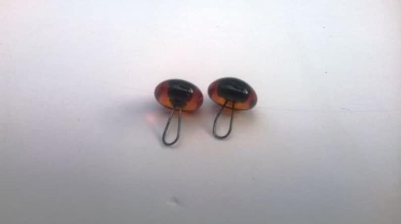 May include: Two brown and black glass eyes with a metal loop on the back. The eyes are for craft projects.