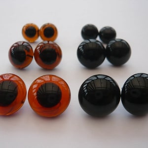 May include: Assortment of brown and black plastic safety eyes for crafts. The eyes are various sizes and have a black pupil.