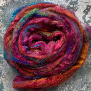 May include: A colorful ball of yarn with shades of red, orange, yellow, green, blue, and purple. The yarn is made of silk and is perfect for knitting or crocheting.