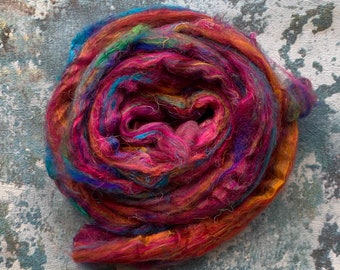 May include: A colorful ball of yarn with shades of red, orange, yellow, green, blue, and purple. The yarn is made of silk and is perfect for knitting or crocheting.