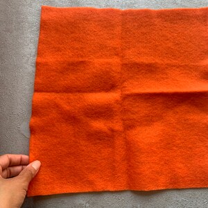 May include: A square piece of orange felt fabric.