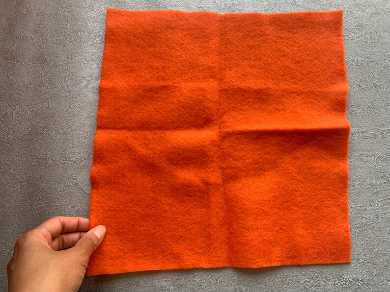 May include: A square piece of orange felt fabric.