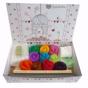 May include: A felting kit in a white box with a colourful birdcage design. The kit includes a variety of coloured wool, a felting needle, a soap bar, and a small bamboo mat.