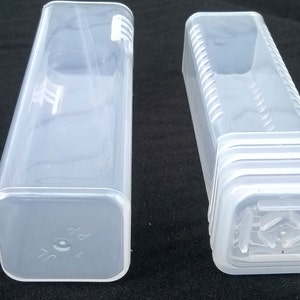 May include: Two clear plastic storage containers with square bases and rectangular sides. The container on the right has a series of ridges around the sides.