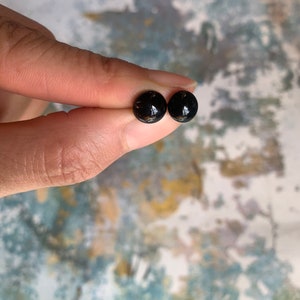 May include: A pair of black stud earrings with a shiny finish.