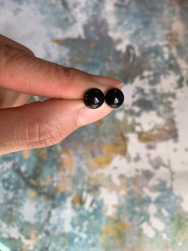 May include: A pair of black stud earrings with a shiny finish.