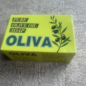May include: A yellow box with green text and a green olive branch illustration. The text reads "PURE OLIVE OIL SOAP OLIVA".