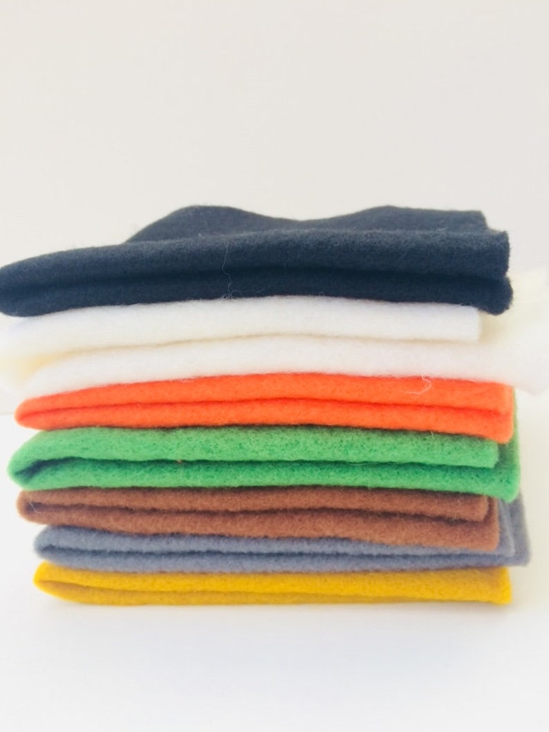 May include: A stack of eight felt squares in various colors, including black, white, orange, green, brown, gray, and yellow.