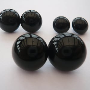 May include: A set of six black onyx gemstone earrings in various sizes. The earrings are round and smooth.