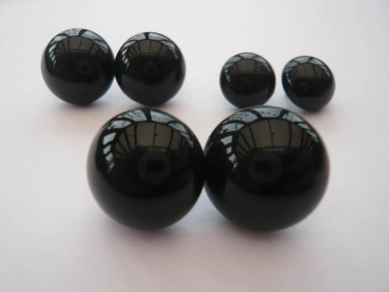 May include: A set of six black onyx gemstone earrings in various sizes. The earrings are round and smooth.