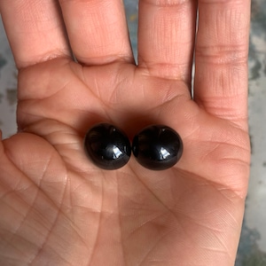 May include: Two black, round, smooth, shiny, glass beads.