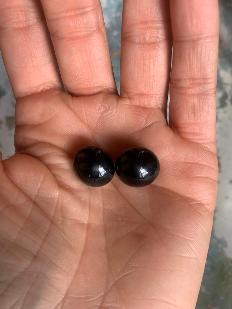 May include: Two black, round, smooth, shiny, glass beads.