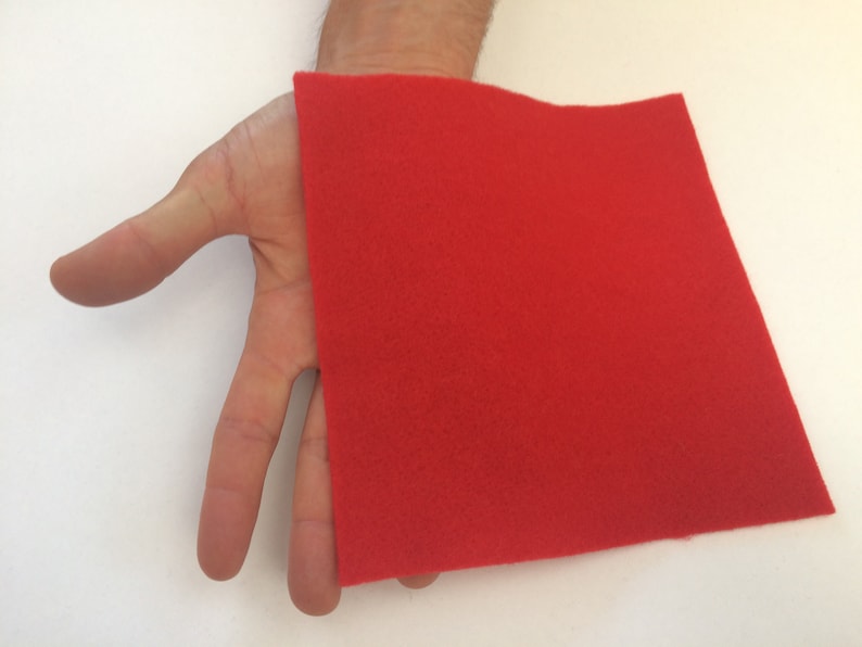 May include: A red felt square, approximately 10 inches by 10 inches, is held in a person's hand.