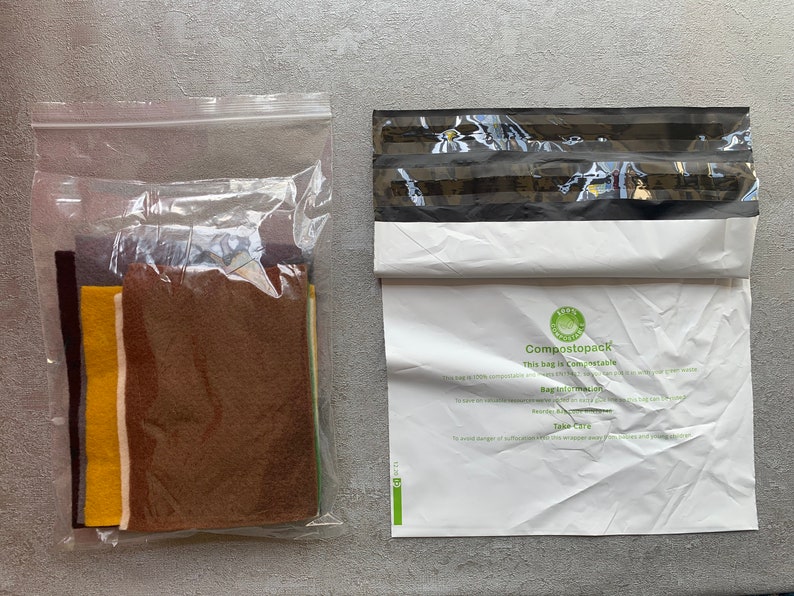 May include: A clear plastic bag filled with various colors of felt fabric. Next to it is a white compostable mailing bag with the text "Compostopack This bag is compostable" printed on it.