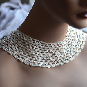 May include: A white crocheted collar necklace with pearl-like beads and rhinestones.