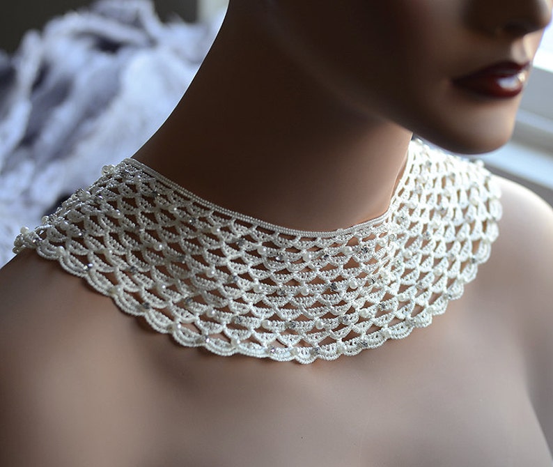 May include: A white crocheted collar necklace with pearl-like beads and rhinestones.