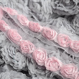 May include: Close-up of a gray and pink fabric with a floral design. The fabric has a delicate, lace-like texture with small, pink flowers.