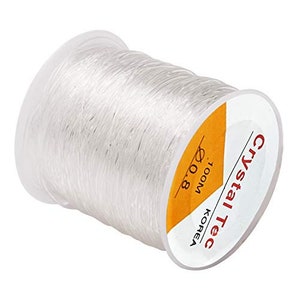 May include: A white spool of elastic string, labeled "Crystal Tec" and "1000M 0.8", with the text "KOREA" printed vertically.