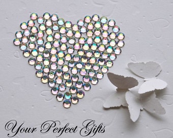 May include: A white card with a heart shape made of iridescent rhinestones and three white paper butterflies. The text "Your Perfect Gifts" is written at the bottom of the card.