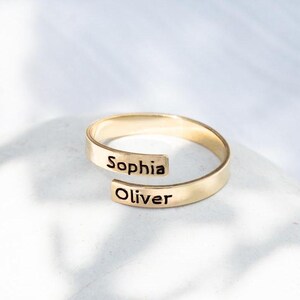 Könnte beinhalten: Ein goldfarbener Ring mit den eingravierten Namen "Sophia" und "Oliver".