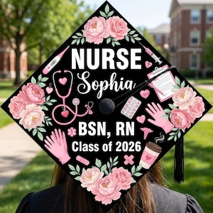 May include: A black graduation cap decorated with pink flowers, medical symbols, and the text "NURSE Sophia BSN, RN Class of 2026." The design includes a stethoscope, syringe, and a coffee cup.