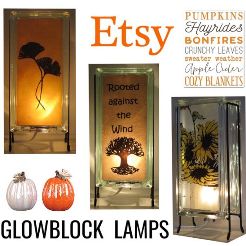 K&ouml;nnte beinhalten: Glowblock-Lampen mit verschiedenen Designs, darunter Ginkgobl&auml;tter, Sonnenblumen und ein Baum mit dem Text "Rooted against the Wind". Die Lampen sind beleuchtet und stehen auf schwarzen Metallst&auml;ndern. Das Wort "Etsy" wird in Orange angezeigt.