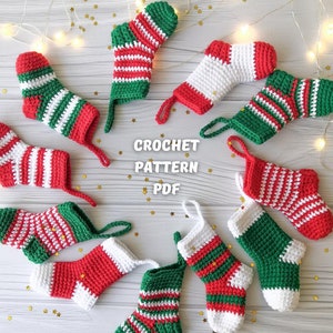 May include: A set of eight crocheted Christmas stockings in red, white, and green. The stockings are arranged in a circle on a white wooden surface. The text "CROCHET PATTERN PDF" is visible in the center of the image.