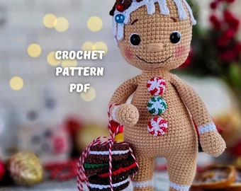 Puede incluir: Muñeco de jengibre de crochet con glaseado blanco, botones de caramelo rojo y verde y un bastón de caramelo marrón. El muñeco sostiene un pastel de jengibre de crochet con glaseado rojo y blanco.