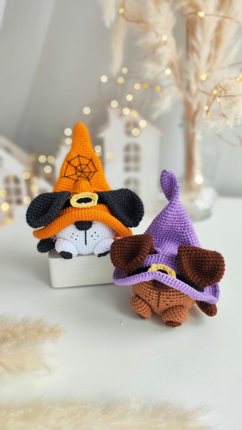 May include: Two crocheted Halloween witch dog toys. One is wearing an orange hat with a black spiderweb and the other is wearing a purple hat.