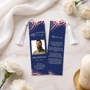 May include: Two rectangular memorial bookmarks with white tassels, featuring a blue background and American flag motifs. One side displays a photograph of a person, the name John McCoven, dates 1988-2025, and text. The other side contains a poem.