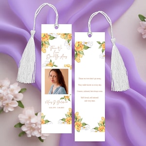 Pode incluir: Dois marcadores brancos com um design floral e uma foto de uma mulher. Os marcadores t&ecirc;m uma borla branca e o texto "Aqueles que amamos n&atilde;o v&atilde;o embora." Os marcadores tamb&eacute;m incluem datas e nomes.