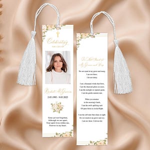 Pode incluir: Dois marcadores comemorativos com borlas brancas. Um marcador apresenta uma foto, o texto "Celebrating the Life of" e o nome e as datas "Rachel McGovern 2.05.1995 - 9.05.2025". O outro tem um poema. Ambos t&ecirc;m detalhes florais.