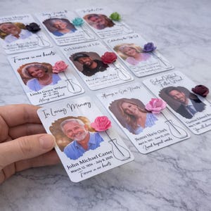 May include: Memorial cards with photos of individuals, each adorned with a paper flower and a vase illustration. The cards feature names, dates, and phrases like "Forever in our hearts" and "In Loving Memory."