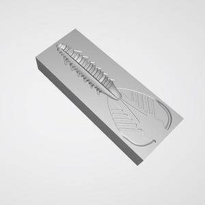 May include: A gray plastic mold for a fishing lure. The mold has a detailed design of a crawfish-style lure, with segmented body and claw details. The mold is rectangular and angled, with a smooth, matte finish.