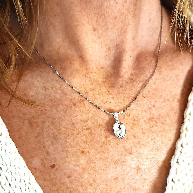 Silver plated coffee bean necklace worn by a model with a white shirt, on a silver snakeskin chain