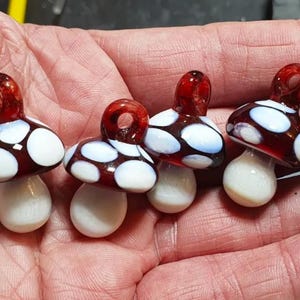 Red and white glass mushroom pendants in hand