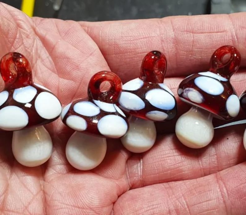 Red and white glass mushroom pendants in hand
