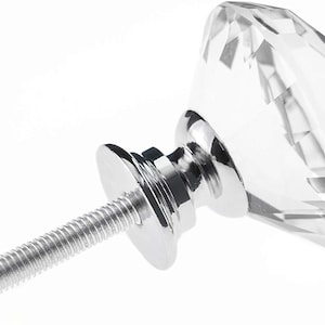 Puede incluir: Un pomo de armario de cristal transparente en forma de diamante con una base de metal plateado y un tornillo.