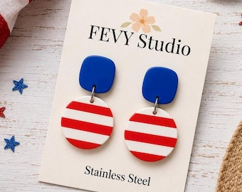 May include: A pair of dangle earrings on a FEVY Studio display card. Each earring features a solid blue square top piece connected to a circular bottom piece with red and white horizontal stripes. The display card is labelled Stainless Steel.