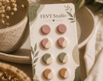以下が含まれることがあります： FEVY Studioと記された台紙に固定された4組の円形スタッドピアス。無地のモーブ色のピアスと、モーブ、セージグリーン、タンの3種類のツートンカラーのピアスがあり、それぞれクリーム色と組み合わされています。台紙にはStainless Steelと記載されています。