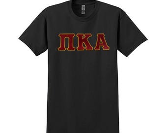 May include: Black t-shirt with the letters "PKA" in red with a gold outline.