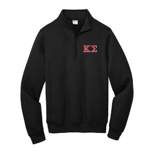 May include: Black quarter-zip sweatshirt with a small red and white embroidered design on the chest. The sweatshirt has a mock neck collar and a zipper that extends down the chest. The design appears to be Greek letters.
