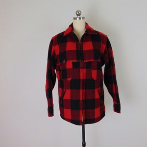 May include: Red and black plaid flannel shirt with a zipper closure. The shirt has two flap pockets on the chest.