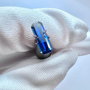May include: A deep blue gemstone ring with a rectangular cut stone set in a silver band.