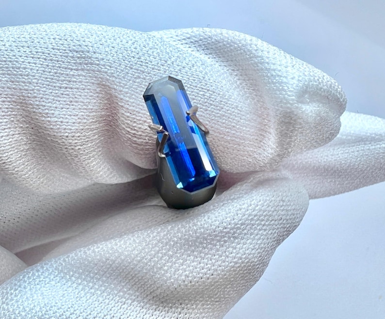 May include: A deep blue gemstone ring with a rectangular cut stone set in a silver band.