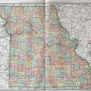 May include: A vintage map of the state of Missouri, showing county boundaries and major roads. The map is printed in shades of green, yellow, pink, and blue. The map is titled "Rand McNally & Company's Indexed Atlas of the World".