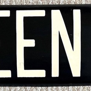 May include: Black and white sign with the text "E. QUEEN ANNE" in white letters on a black background.