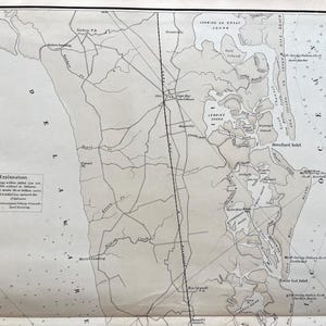 May include: A vintage map with detailed line drawings of a coastal region, featuring inlets, islands, and place names. The map is in grayscale, with text labels and a key in the lower left corner. The paper has a slightly aged appearance.