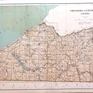 May include: A vintage map titled Chautauqua and Cattaraugus Counties, featuring a tan landmass with black text labels for towns and roads, a light blue Lake Erie, and a grid border. The map includes detailed topography and geographic boundaries.