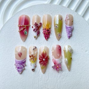 Faux ongles floraux 3D luxueux | Motif floral 3D avec accents de pierres précieuses | Nail art artistique | Boutons pression élégants roses et violets